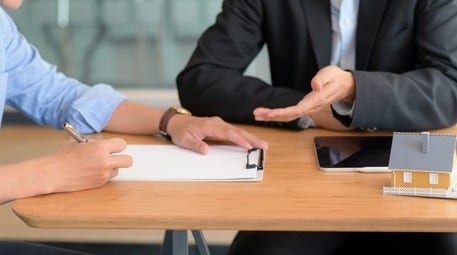 Interviewer and Interviewee sitting at a table with a clipboard