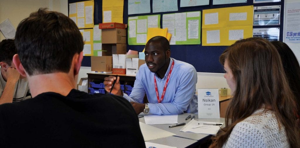 Black male tutor working with a group of students.